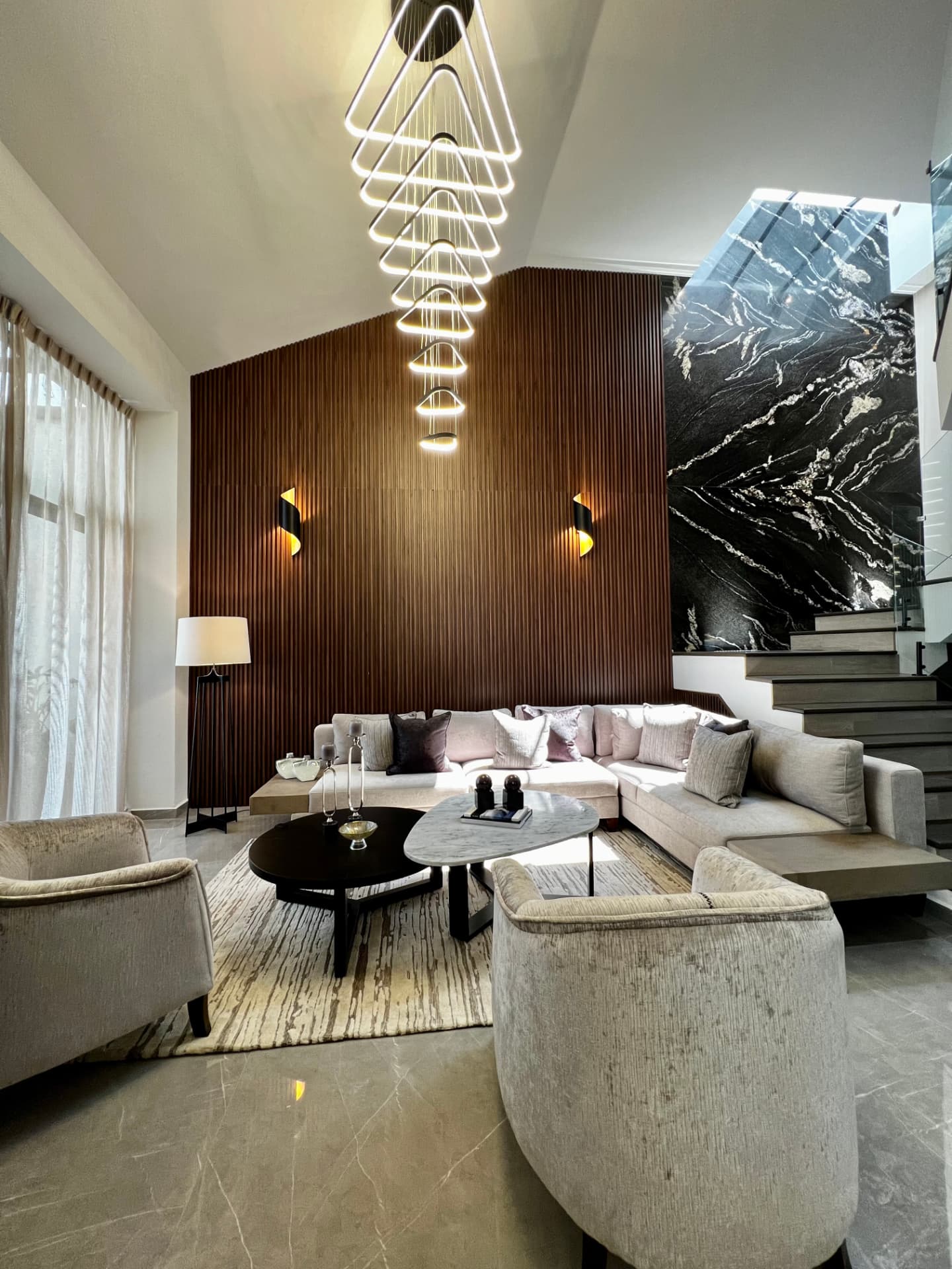 Sala de doble altura con madera y mármol, referencia visual de otra propiedad